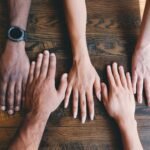 five human hands on brown surface